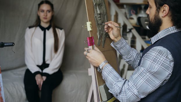 Un artiste dessine un portrait d'une modèle assise, dans un atelier artistique.
